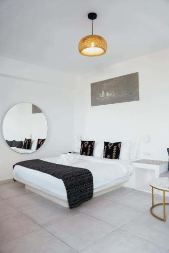 a white bedroom with a bed and a mirror at Lumera Suites in Firostefani