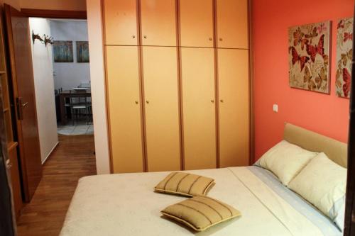1 Schlafzimmer mit orangefarbenen Wänden und 1 Bett mit 2 Kissen in der Unterkunft Ouranos Apartment in Athen