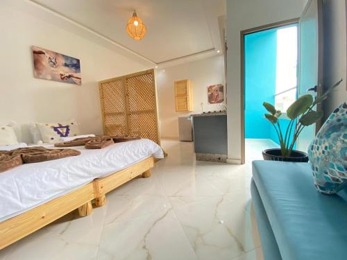 a bedroom with a large bed and a blue couch at KAZA Wave Surf camp in Imsouane