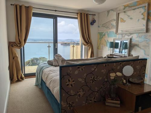 a bedroom with a bed and a large window at Panoramic sea views, sleeps 4, Torquay in Torquay