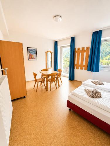 a bedroom with a bed and a table and chairs at Hindenburg-Dependance Hotel Krone in Bad Gastein