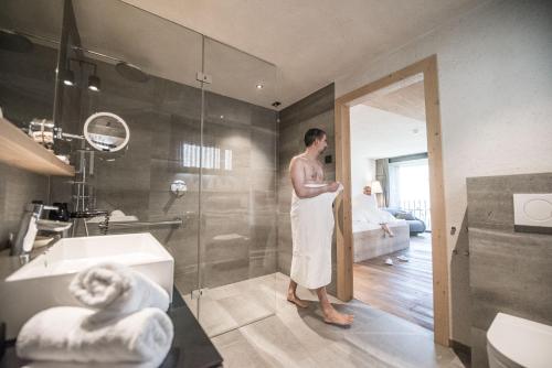 a man standing in a bathroom with a shower at Hotel Krondlhof in Brunico