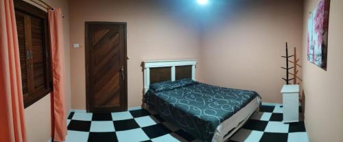 a bedroom with a bed and a black and white checkered floor at Chalé casa na mata Jasmim in Guararema