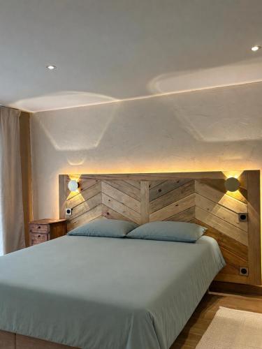 a bedroom with a large bed with a wooden headboard at Hôtel Aghjola in Pioggiola