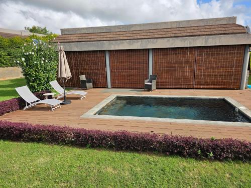 a deck with a pool and two chairs and an umbrella at Private Secured 4 Bedroom Villa in Grand-Baie