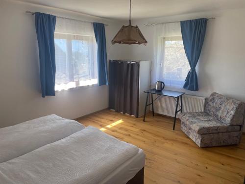 a bedroom with a bed and a chair and windows at Pension Victoria in Millstatt