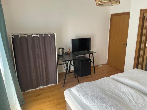 a bedroom with a bed and a desk with a television at Pension Victoria in Millstatt