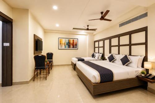 a hotel room with two beds and a table and chairs at Hotel Comfort Park - Opposite Sri Ramachandra Medical College Porur in Chennai