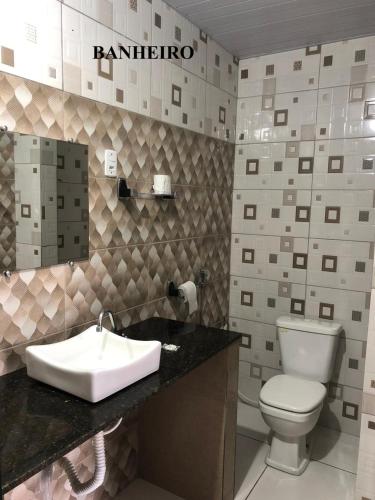 a bathroom with a white toilet and a sink at Pousada Aruanã in Soure