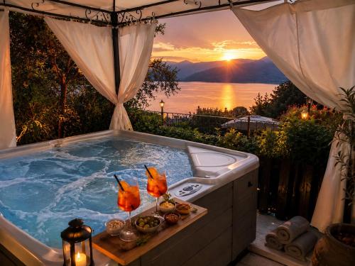 a jacuzzi tub with a sunset in the background at Panoramic Lake View Apartments with Pool & Breakfast in Torri del Benaco