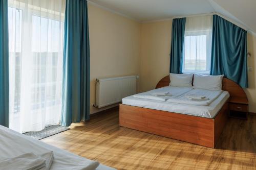 a bedroom with a large bed with blue curtains at Hotel Doina 2 Tasnad in Tăşnad