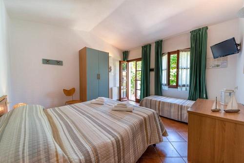 a bedroom with two beds with green curtains at Hotel Voce del Mare in Capoliveri