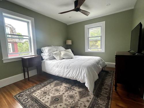 a bedroom with a bed and a ceiling fan at Steps to Derby Wharf and Gables. in Salem