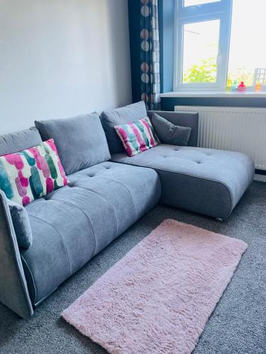 a blue couch in a living room with a pink rug at Godrevy Lighthouse View, Carbis Bay, St Ives, free parking, sea view in Carbis Bay