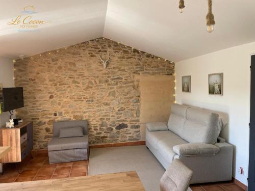 a living room with a couch and a stone wall at Le Cocon des Forges in Talmont