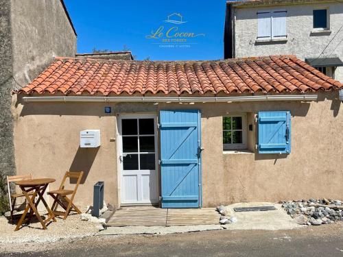 a small house with blue doors and a table at Le Cocon des Forges in Talmont