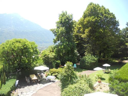 a garden with tables and umbrellas and trees at Hotel Bellevue in Ayse