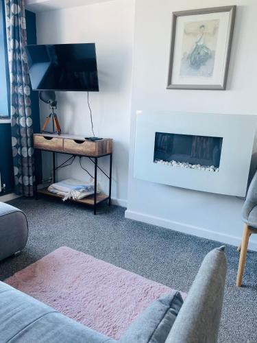 a living room with a fireplace and a tv at Godrevy Lighthouse View, Carbis Bay, St Ives, free parking, sea view in Carbis Bay