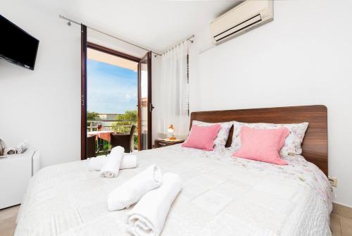 a bedroom with a large white bed with pink pillows at Guesthouse Santin in Rovinj
