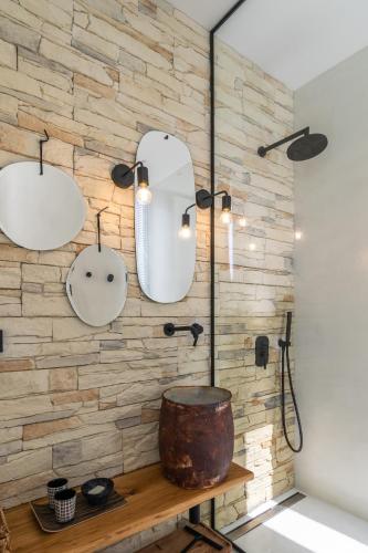 a bathroom with a stone wall with two mirrors and a tub at THEIA VILLA in Adamantas