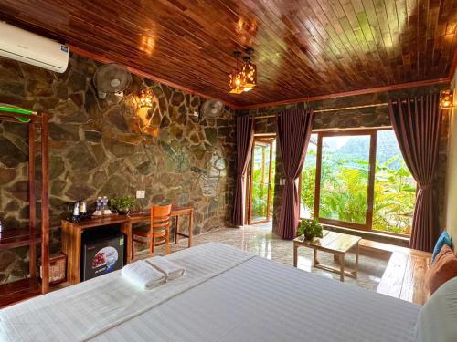 a bedroom with a bed and a stone wall at Rocky Mountain Ecolodge in Xuân Sơn