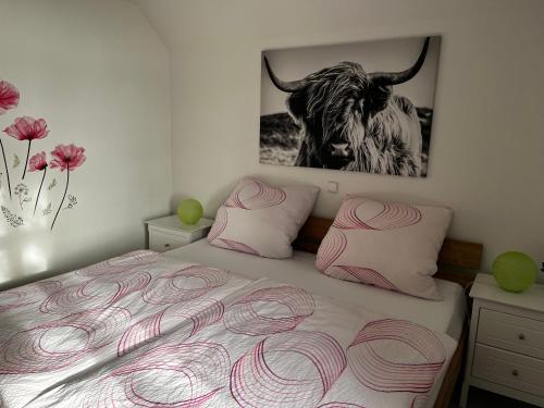 a bedroom with a bed with a bull picture on the wall at Landhaus Baumhöfer in Apen