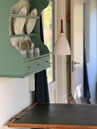 a table with a green shelf with dishes on it at Tiny house close to Copenhagen in Nybølle