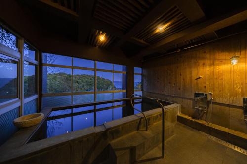 a large bathroom with a tub with a window at 鵜原館 -Ubarakan- in Katsuura