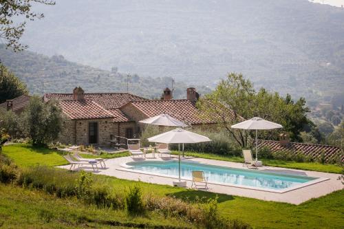 a swimming pool in front of a house with umbrellas at San Martino agli Ulivi in Cortona