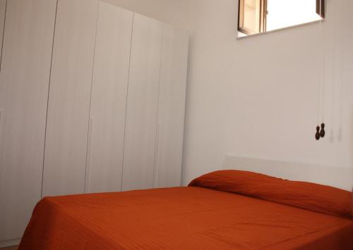 a bedroom with a bed with an orange blanket at Iaia Apartment in Sciacca