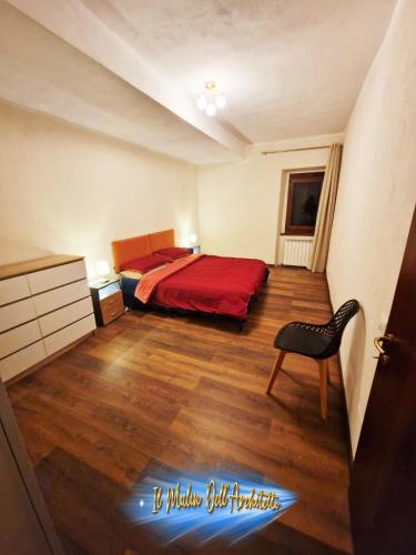a bedroom with a red bed and a chair at Il Mulin Dell'Architetto in Fornaci di Barga