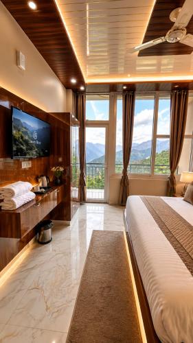 a bedroom with a large bed and a tv at Hotel Himalayan Heaven - A Most Luxury & Best Mountain View Hotel In Mussoorie By lilly in Mussoorie