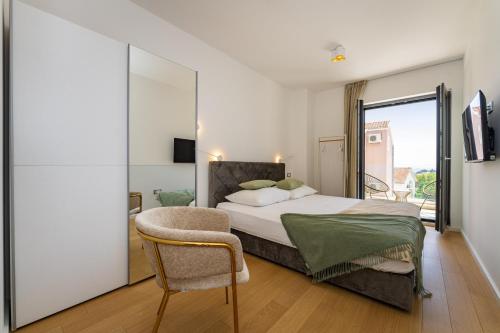 a bedroom with a bed and a chair and a window at Villa Cvita west in Primošten