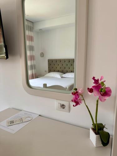 un bagno con uno specchio e un vaso con un fiore di Elena Hotel a Sarandë
