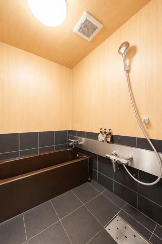 a bathroom with a bath tub and a shower at OYASUMI Art HOTEL Dotonbori 24-Hour Check-in Pressure-relief mattress in Osaka