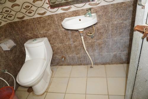 a bathroom with a toilet and a sink at Hotel Raj Resort and Pool in Dogeta