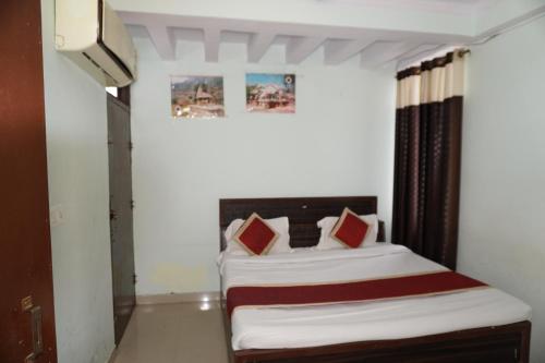 a bedroom with a bed with red and white pillows at Hotel Raj Resort and Pool in Dogeta