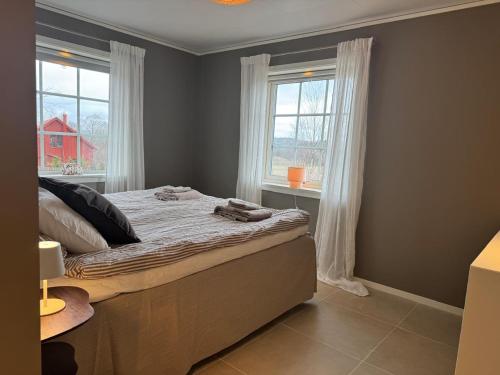 a bedroom with a large bed with two windows at Backahöjd Holidays in Rävlanda
