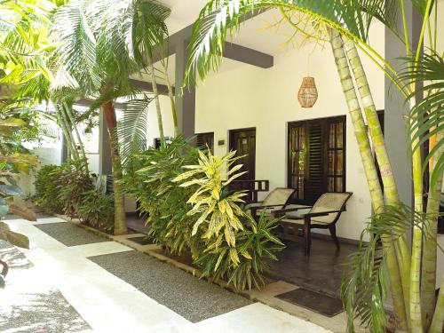 a courtyard with palm trees and a table and chairs at Agra Arugambay in Arugam Bay