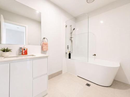 a white bathroom with a tub and a sink at 21 Pimpama Home in Pimpama