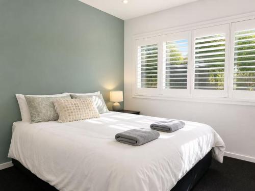 a bedroom with a large white bed with two towels on it at 21 Pimpama Home in Pimpama