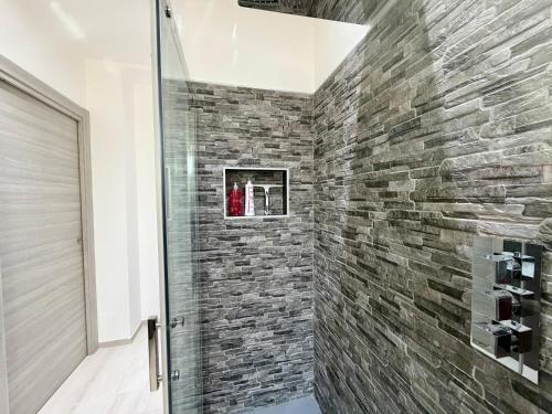 a shower in a bathroom with a stone wall at Wake to Lake - Arona, Lago Maggiore in Arona