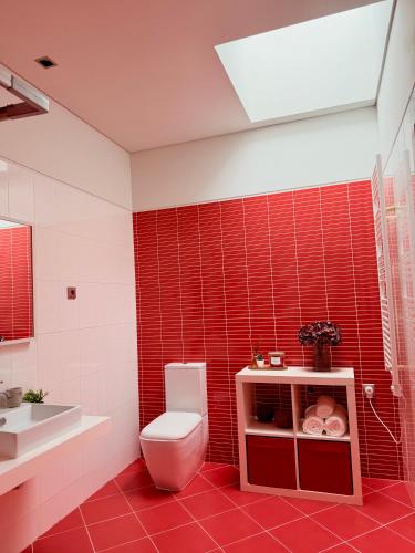 a red tiled bathroom with a toilet and a sink at Ednas Place - Tranquilidade e Natureza in Caminha