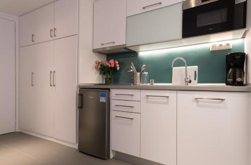 a kitchen with white cabinets and a stainless steel refrigerator at Homz Studios Faliro in Athens