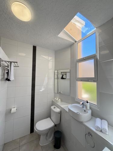 a bathroom with a toilet and a sink and a window at Yucca Park ApartHotel in Adeje