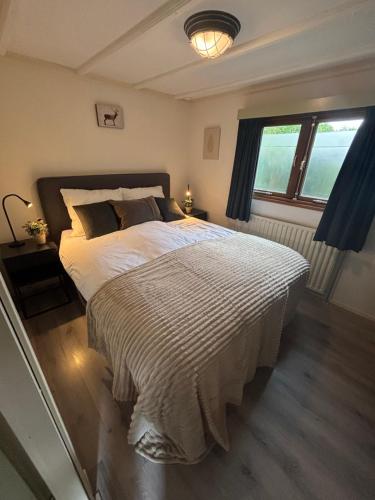 a bedroom with a large bed and a window at Chalet Wild Forest, knus chalet op de Veluwe met gratis parkeren in Putten