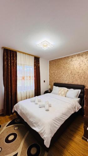 a bedroom with a large bed with white sheets and a window at Casa Izvorul Muntelui in Sadova