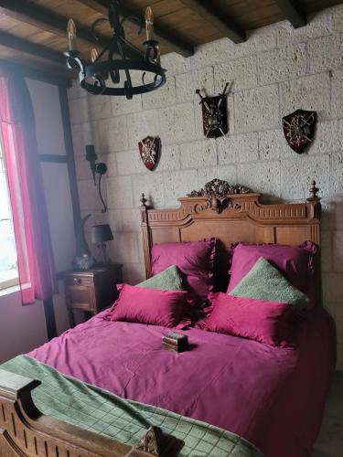 a bedroom with a large bed with purple sheets and pillows at Maison Médiévale LAON in Laon