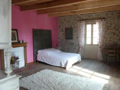 a bedroom with a white bed and a pink wall at Gîte La Mirgue in Sanvensa