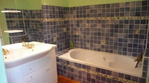 a bathroom with a tub and a sink at Gîte La Mirgue in Sanvensa